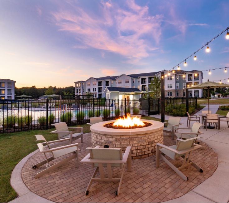 firepit lounge sunset string lights building exterior paver patio shrubbery
