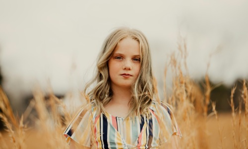 little girl standing in a field tall grass striped dress blonde hair little girl standing in a field tall grass striped dress blonde hair